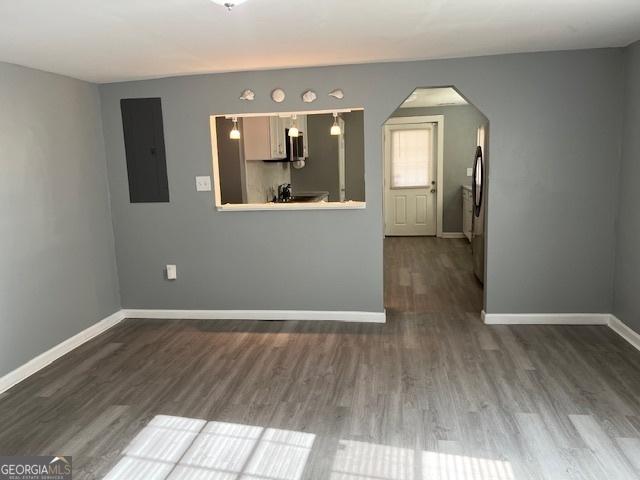 empty room featuring electric panel and wood-type flooring