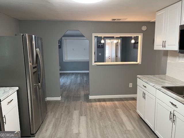 kitchen with white cabinetry, light hardwood / wood-style flooring, light stone countertops, and appliances with stainless steel finishes