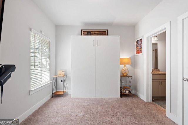 carpeted bedroom with ensuite bathroom and multiple windows