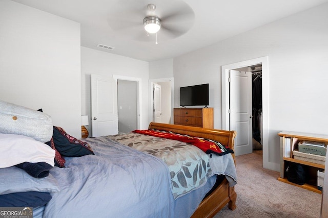 bedroom with ceiling fan, light colored carpet, a spacious closet, and a closet