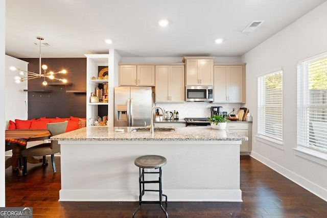 kitchen featuring light stone countertops, pendant lighting, stainless steel appliances, and sink