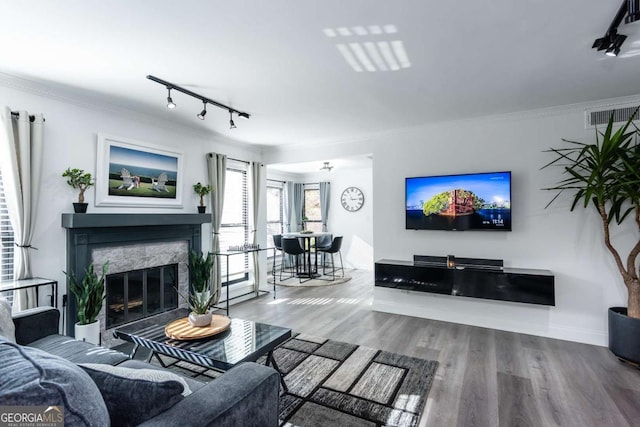 living room featuring hardwood / wood-style flooring, ornamental molding, a fireplace, and track lighting