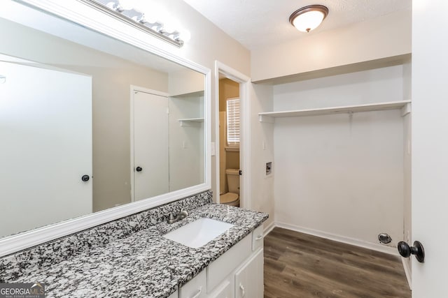 bathroom featuring vanity, wood-type flooring, a textured ceiling, and toilet