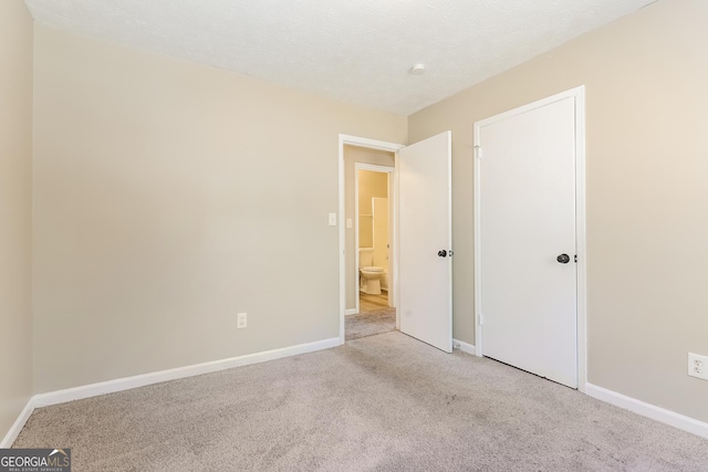 unfurnished bedroom featuring light colored carpet and a textured ceiling