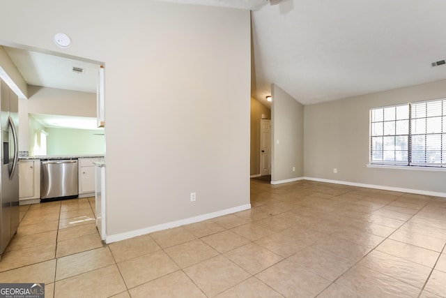 tiled spare room featuring lofted ceiling