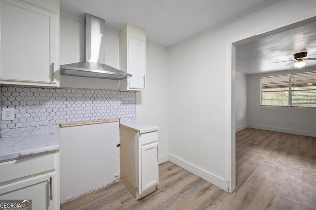 kitchen featuring white cabinets, wall chimney exhaust hood, light wood-type flooring, and tasteful backsplash