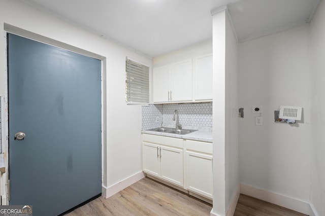 interior space featuring electric dryer hookup, sink, and light hardwood / wood-style flooring