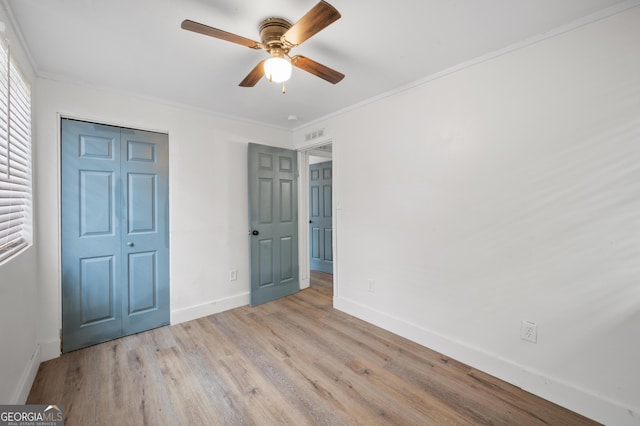 unfurnished bedroom featuring light wood-type flooring, a closet, ornamental molding, and ceiling fan
