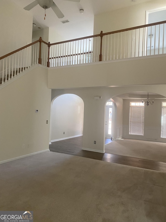 interior space featuring ceiling fan with notable chandelier, a towering ceiling, and carpet floors