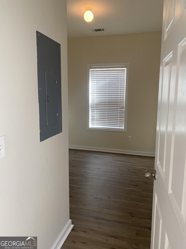 spare room with electric panel and dark wood-type flooring