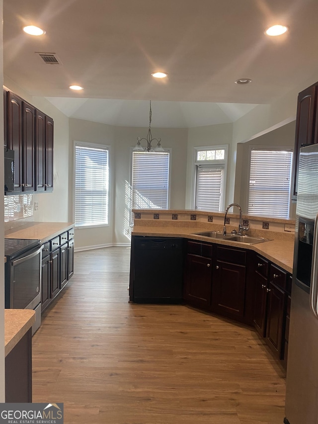 kitchen featuring sink, hanging light fixtures, light hardwood / wood-style floors, a chandelier, and appliances with stainless steel finishes