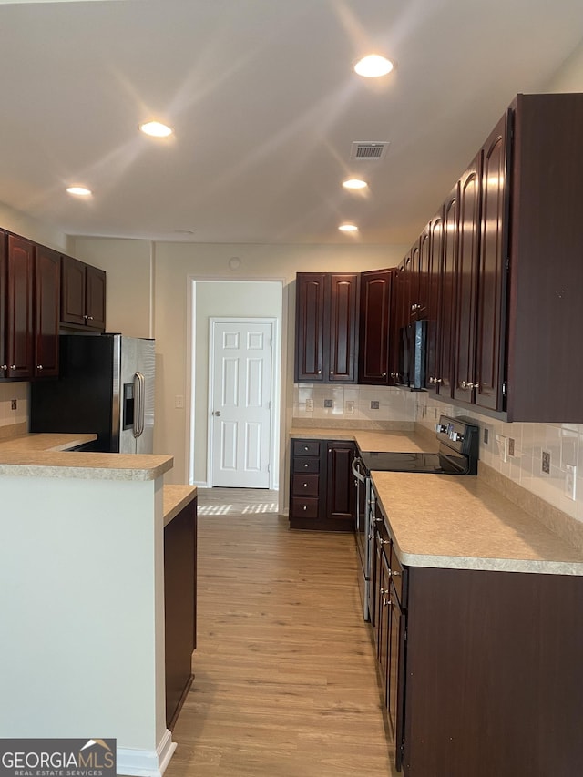 kitchen featuring light wood-type flooring, dark brown cabinets, backsplash, and black appliances