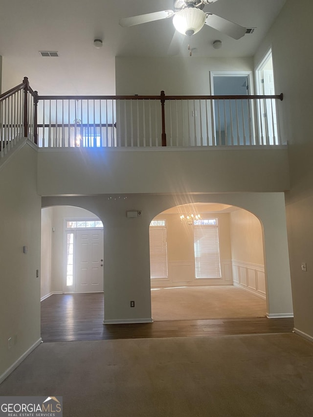 interior space with a high ceiling, ceiling fan with notable chandelier, and wood-type flooring