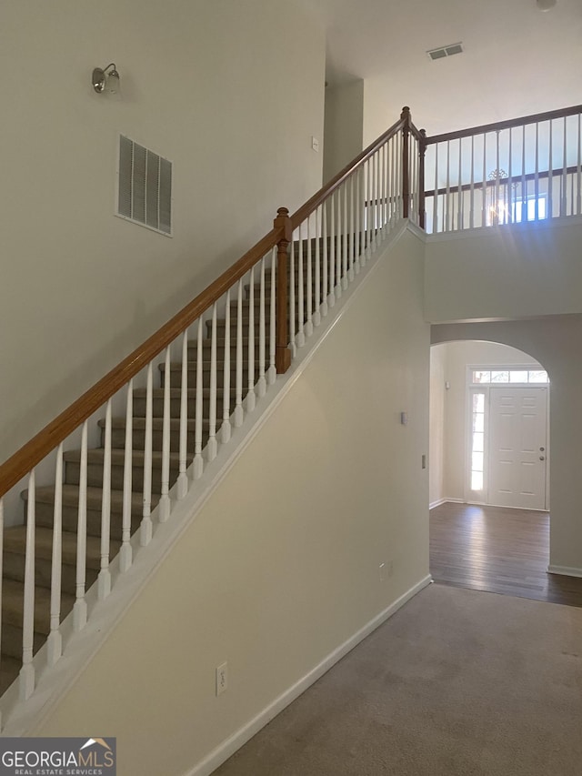 stairs with carpet floors and a high ceiling