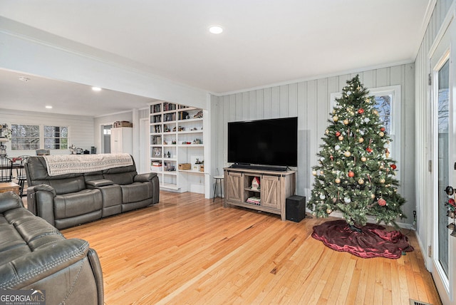 living room with hardwood / wood-style flooring, built in features, and ornamental molding