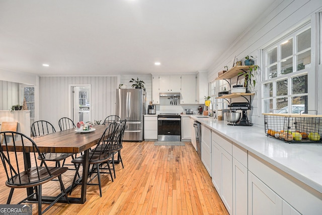 kitchen featuring sink, light hardwood / wood-style flooring, washer / clothes dryer, white cabinets, and appliances with stainless steel finishes