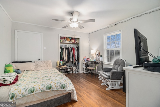 bedroom with ceiling fan, wood-type flooring, crown molding, and a closet