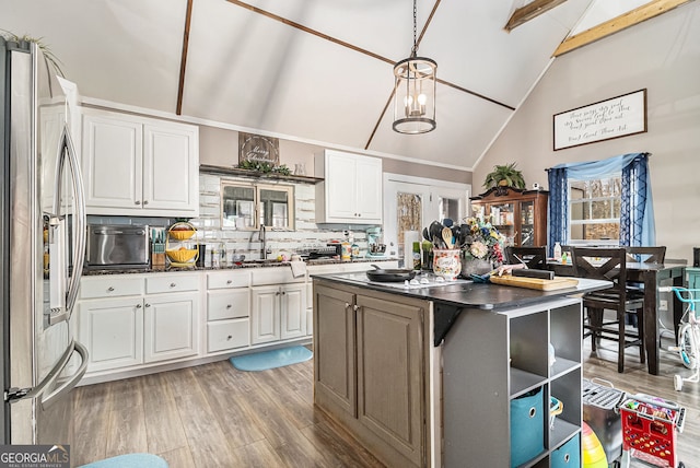 kitchen featuring vaulted ceiling with beams, white cabinetry, a center island, and decorative backsplash