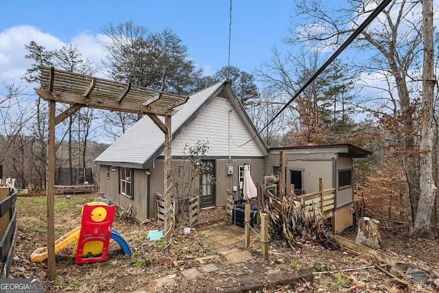 back of property featuring a pergola and a trampoline