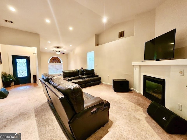 living room with ceiling fan, light colored carpet, and high vaulted ceiling