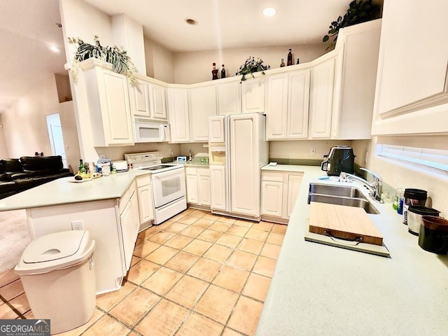 kitchen featuring white appliances, sink, a towering ceiling, white cabinetry, and kitchen peninsula