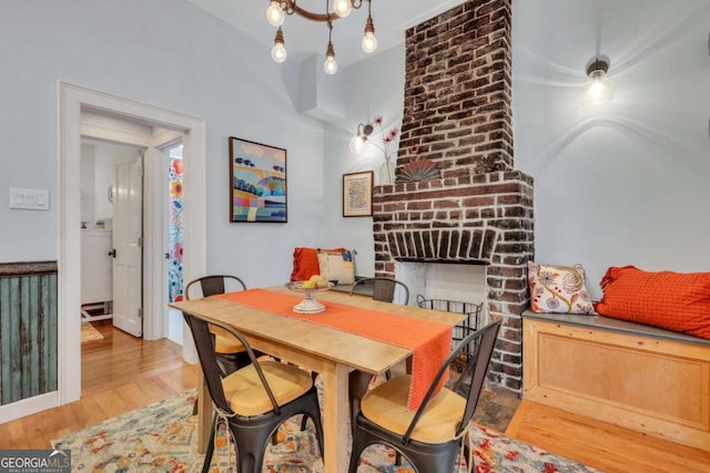 dining room featuring a chandelier, light hardwood / wood-style floors, and a brick fireplace