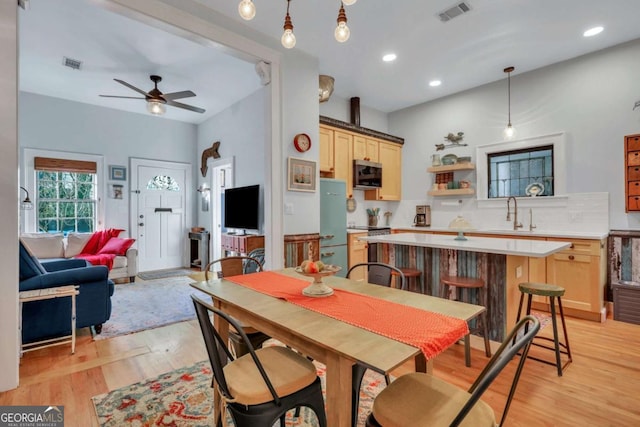 dining room featuring ceiling fan, sink, and light hardwood / wood-style flooring