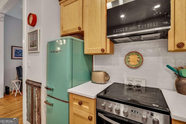 kitchen featuring decorative backsplash, light brown cabinets, electric stove, and fridge