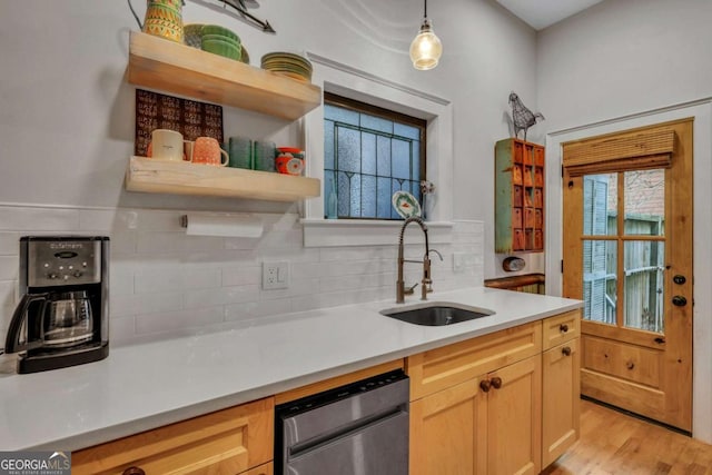 kitchen with backsplash, light brown cabinetry, sink, and decorative light fixtures