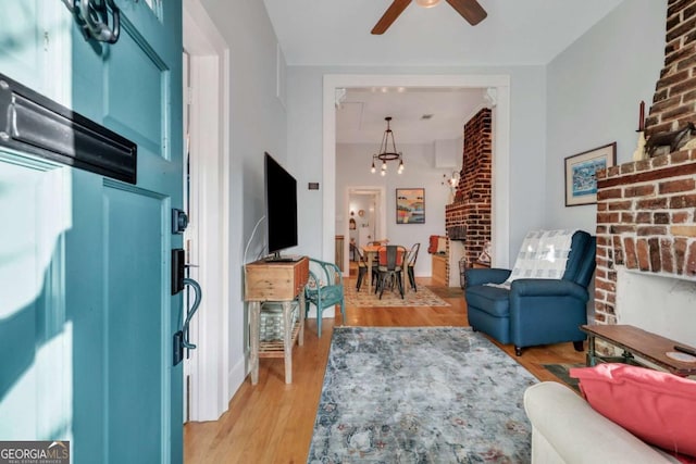 living room featuring ceiling fan with notable chandelier and light hardwood / wood-style floors