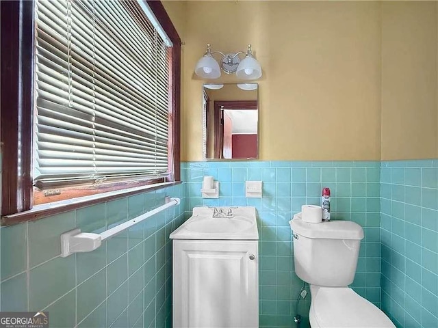 bathroom featuring vanity, toilet, and tile walls