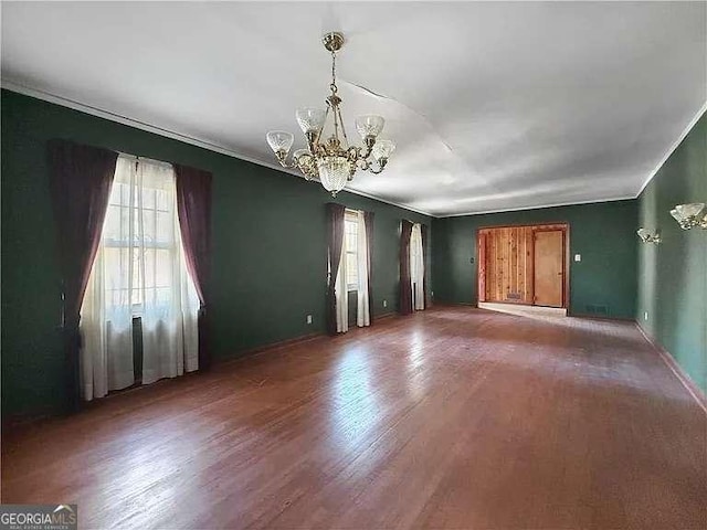 spare room with hardwood / wood-style flooring and an inviting chandelier