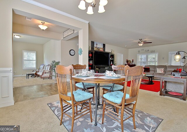 carpeted dining room with ceiling fan with notable chandelier