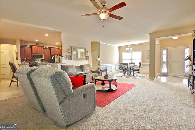 carpeted living room with ceiling fan with notable chandelier