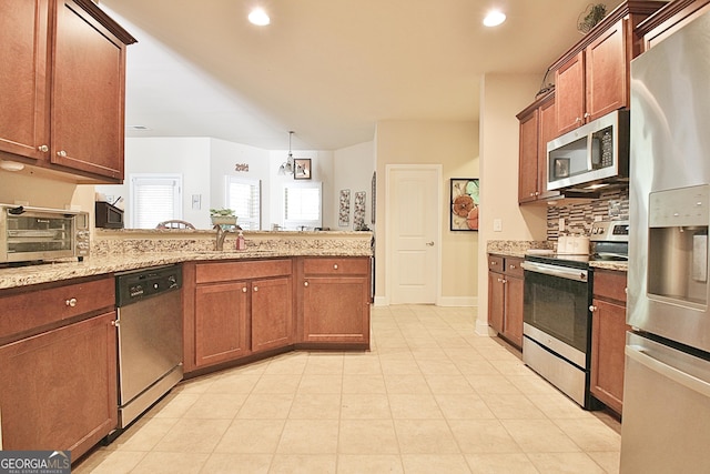 kitchen featuring appliances with stainless steel finishes, decorative light fixtures, sink, decorative backsplash, and light stone countertops