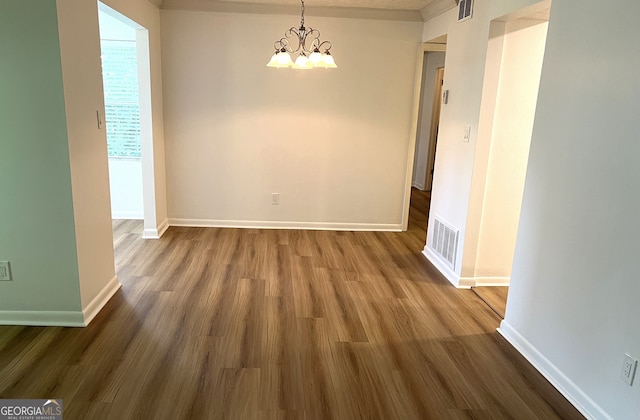 unfurnished dining area with dark wood-type flooring and a notable chandelier