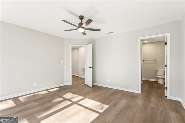 unfurnished bedroom with ceiling fan, ensuite bath, and hardwood / wood-style flooring