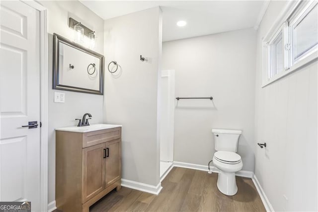 bathroom featuring walk in shower, hardwood / wood-style floors, vanity, and toilet