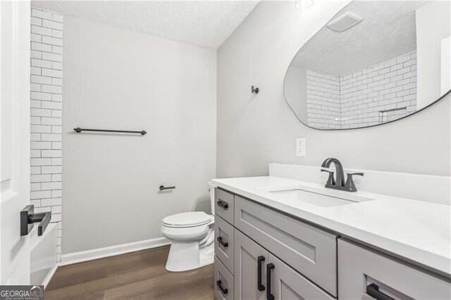 full bathroom featuring a textured ceiling, toilet, shower / washtub combination, vanity, and hardwood / wood-style flooring