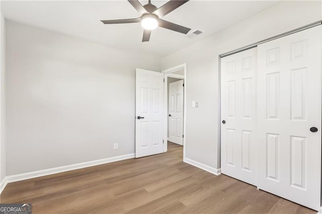 unfurnished bedroom featuring ceiling fan, light hardwood / wood-style floors, and a closet