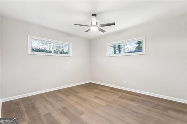 empty room with ceiling fan, plenty of natural light, and hardwood / wood-style floors