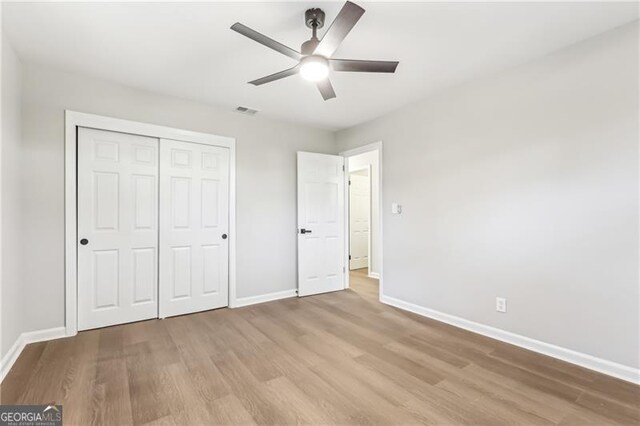 unfurnished bedroom with ceiling fan, light hardwood / wood-style floors, and a closet