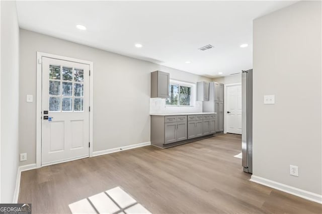 kitchen featuring tasteful backsplash, gray cabinetry, stainless steel fridge, and light hardwood / wood-style floors