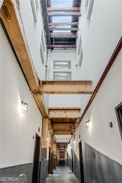 hallway featuring beamed ceiling and a high ceiling