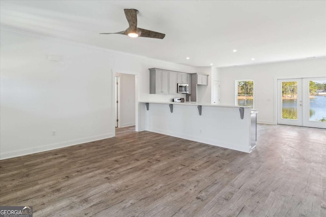 kitchen featuring gray cabinetry, ceiling fan, french doors, kitchen peninsula, and a breakfast bar