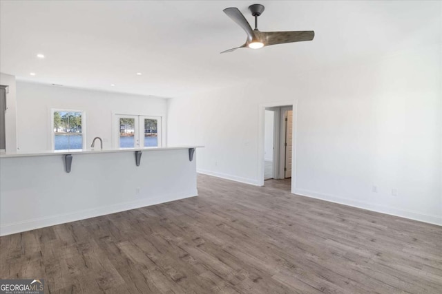 unfurnished living room featuring wood-type flooring, french doors, ceiling fan, and sink