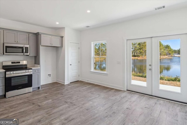 kitchen featuring gray cabinetry, french doors, a water view, and appliances with stainless steel finishes