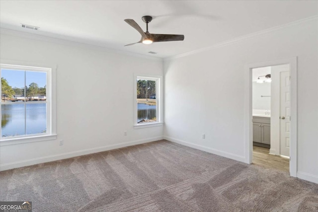 spare room with ceiling fan, ornamental molding, light carpet, and a wealth of natural light