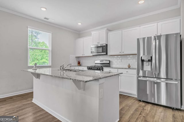 kitchen with white cabinetry, sink, light stone counters, an island with sink, and appliances with stainless steel finishes