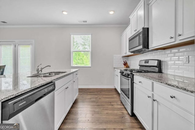 kitchen with appliances with stainless steel finishes, light stone counters, dark wood-type flooring, sink, and white cabinets